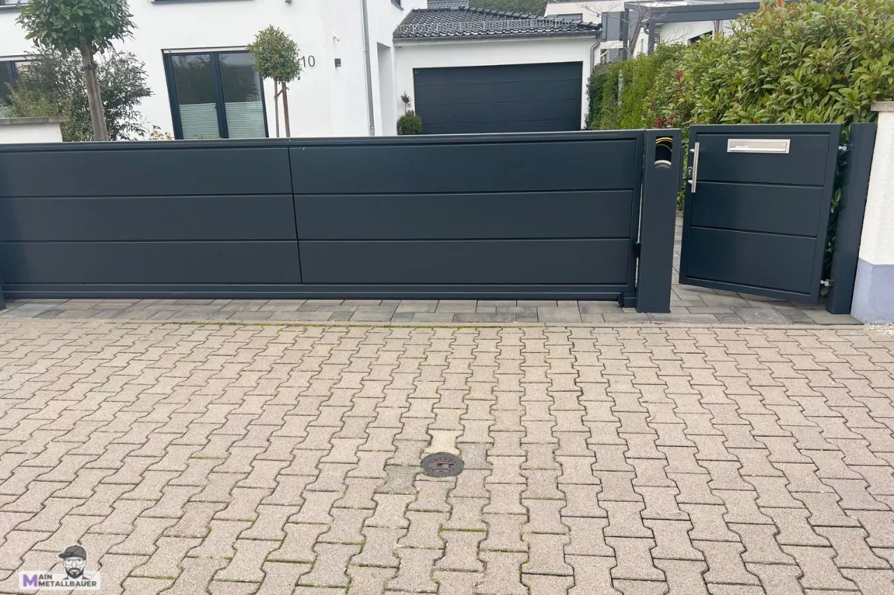 Freitragendes Schiebetor mit Tuer integriertem Briefkasten und Gegensprechanlage Freitragendes Schiebetor mit Tuer pulverbeschichtet in Anthrazit integriertem Briefkasten und Gegensprechanlage