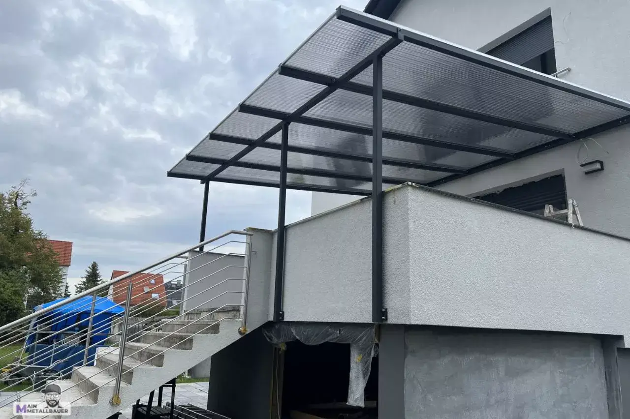 Terassenueberdachung aus Stahl mit verdunkelten Polycarbonatplatten